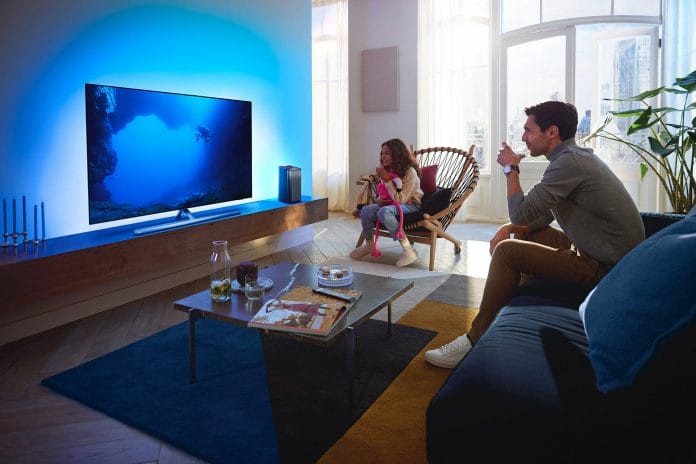 Philips OLED807 4K OLED TV mit schwenkbaren T-Standfuß und dem Fidelio FS1 Satelliten-Lautsprecher (rechts)